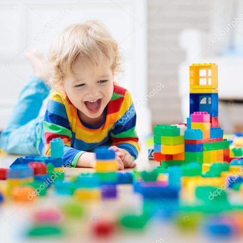 Child playing with colorful toy blocks. Little boy building tower at home or day care. Educational toys for young children. Construction block for baby or toddler kid. Mess in kindergarten play room.